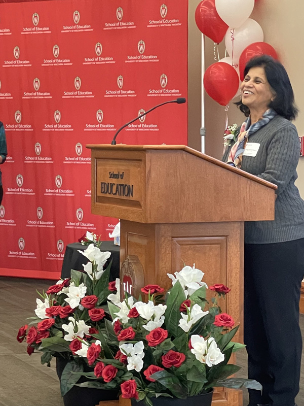 Puntambekar standing at a podium that has School of Education on the front of it.