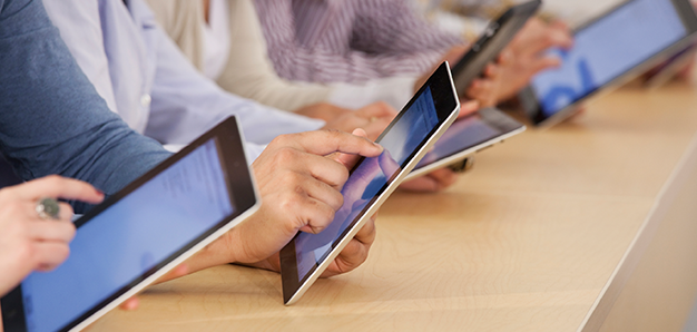 Close up view of five people's hands using tablets